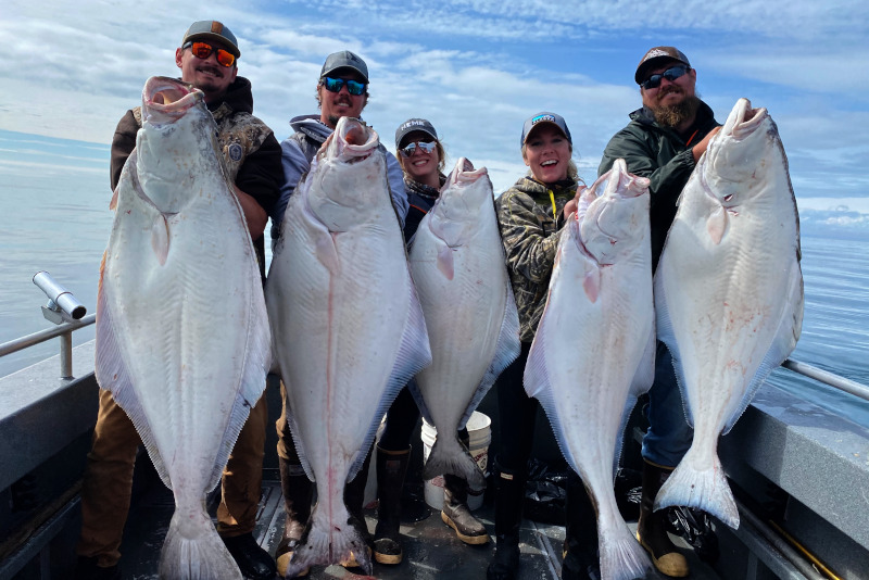 people holding halibut on Cook Inlet in Ninilchik Alaska